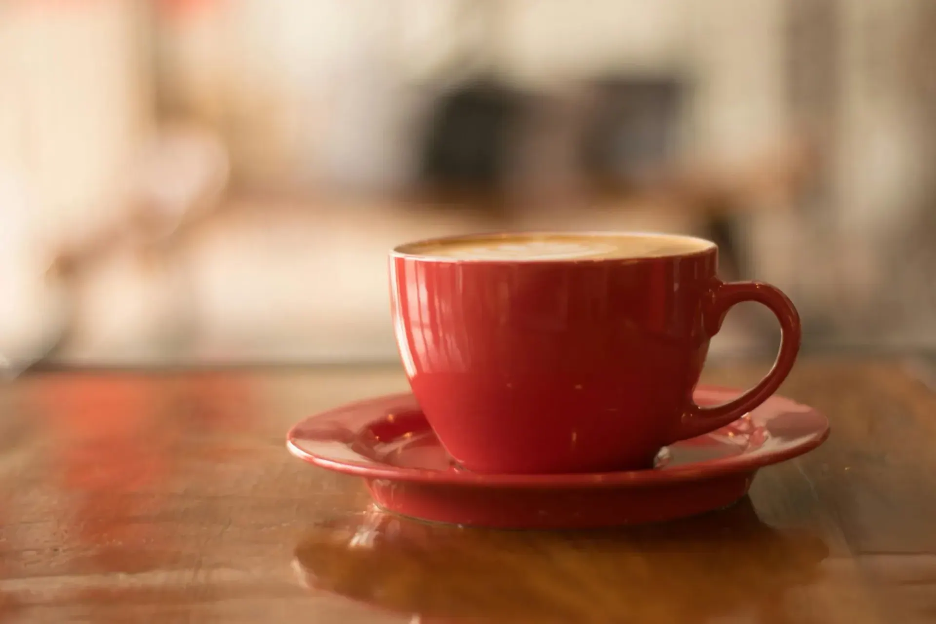 Taza roja de café con espuma sobre una mesa de madera