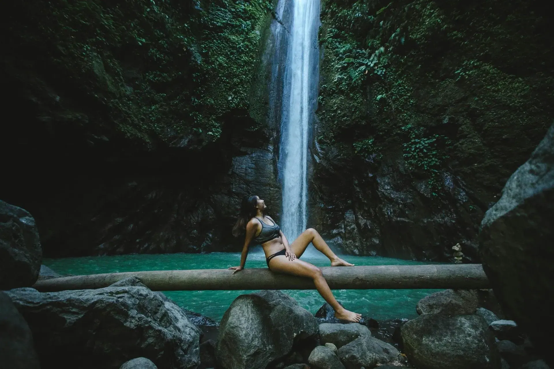 Mujer sentada frente a una catarata en el bosque