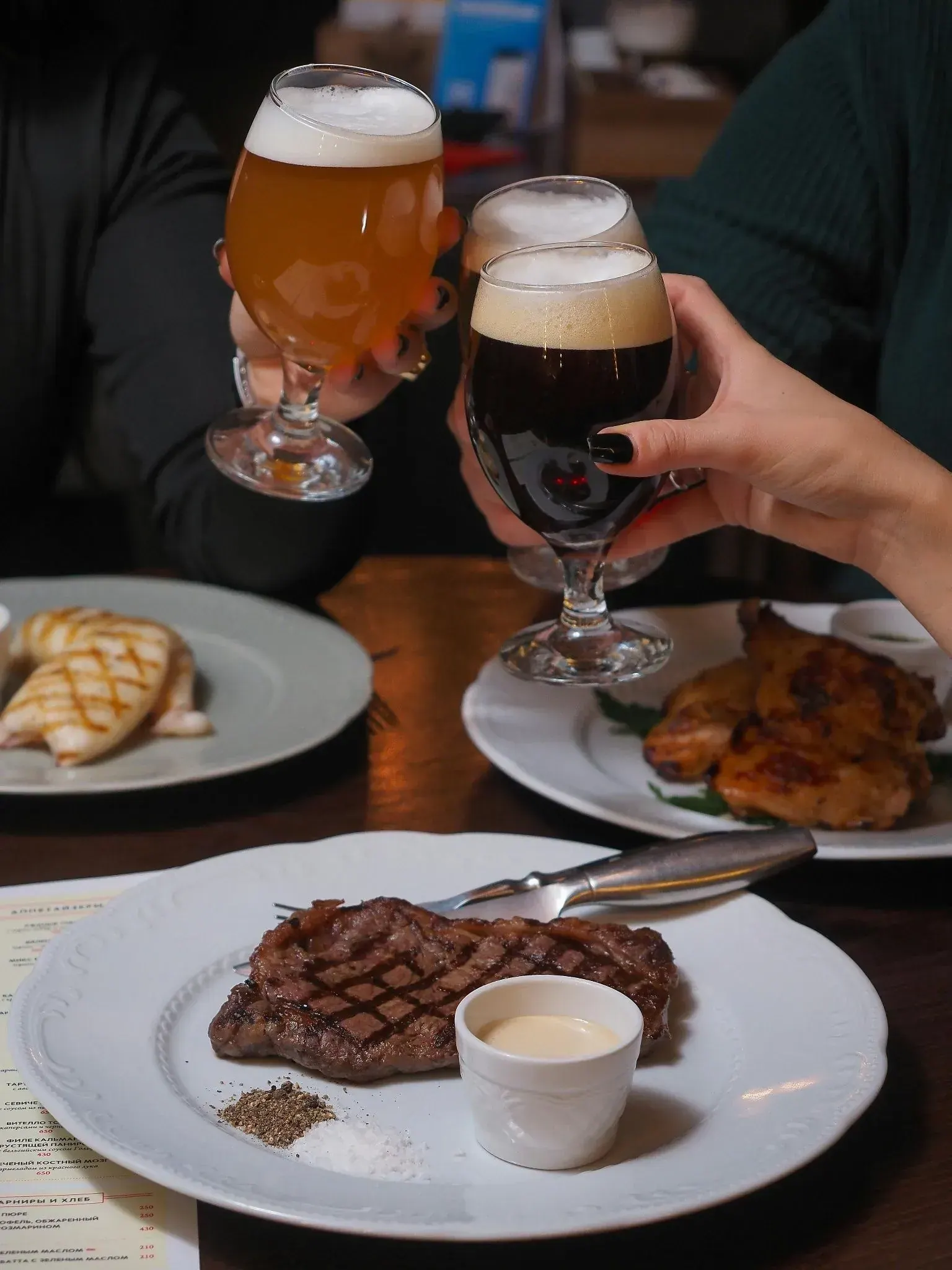 Cervezas artesanales brindando junto a platos de carne